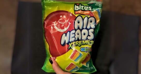 a womans hand holding a large bag of airheads extreme bite candy