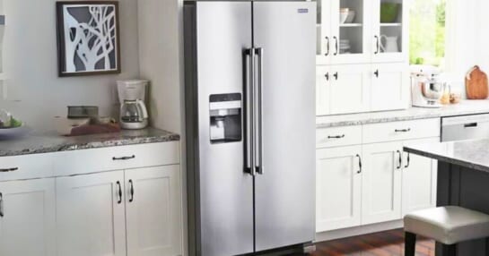 Maytag stainless steel side by side fridge in a kitchen with white cabinets and granite countertop
