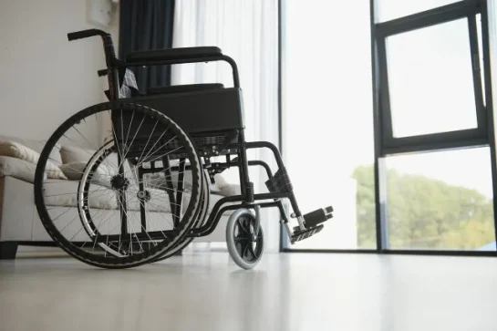 Empty wheelchair in living room next to the couch