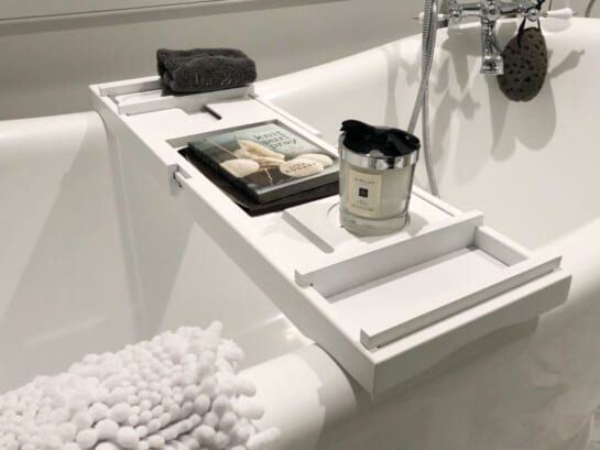 white bath tray across bathtub with drink and book sitting on top