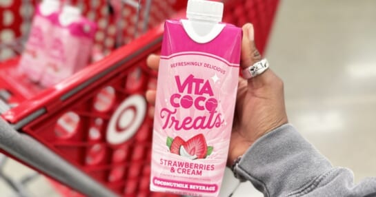 hand holding up pink carton of Vita Coco Strawberries & Cream Treats Coconutmilk in front of target shopping cart