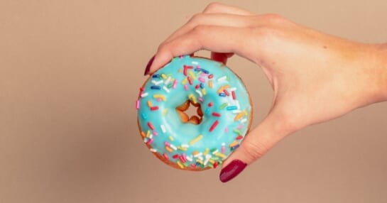 holding a doughnut with blue glaze and sprinkles