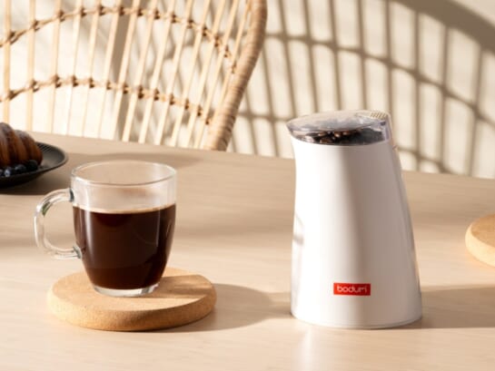 Coffee grinder with a cup of coffee cup on the table